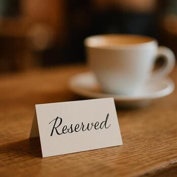 Masada kalemle yazılmış küçük rezervasyon notu ve kahve bardağı